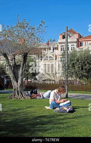 Jardim das Oliveiras Frau sitzt von olivenbaum SMS auf Handy außen Lello Buchladen Gebäude Praça de Lisboa Porto Portugal KATHY DEWITT Stockfoto