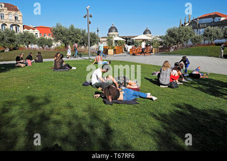 Blick auf Olivenbäume & Menschen Schüler entspannten Sitzen auf dem Rasen durch Base Porto Cafe auf dem grünen Dach Park von der Praça de Lisboa Porto KATHY DEWITT Stockfoto