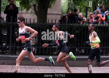 Callum Hawkins (GBR), Yassine Rachik (ITA) und Bashir Abdi (BEL), kämpft es sich um Canary Wharf, während der 2019 London Marathon. Sie fuhr fort, zu 10., 9. und 7. Jeweils im Elite Rennen der Männer beenden. Stockfoto