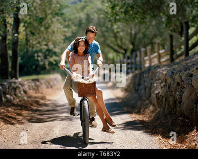 Mann seine Frau Verdoppelung auf einem Fahrrad auf einem Waldweg. Stockfoto