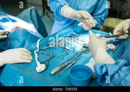 In der Nähe von Doktor Hände während der Operation in Betrieb. Sterilen chirurgischen Instrumenten in einem realen Betrieb verwendet. Schwerpunkt liegt auf der Zeile der Klemmung Griffe. Stockfoto