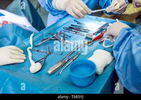 In der Nähe von Doktor Hände während der Operation in Betrieb. Sterilen chirurgischen Instrumenten in einem realen Betrieb verwendet. Schwerpunkt liegt auf der Zeile der Klemmung Griffe. Stockfoto