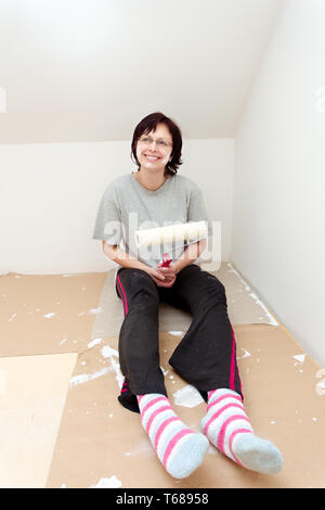 Hausfrau Ausruhen nach Malerei Wand zu Weiß Stockfoto