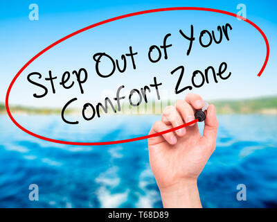 Mann Hand schreiben Schritt aus Ihrer Komfortzone mit schwarzem Marker auf visuelle Bildschirm. Stockfoto
