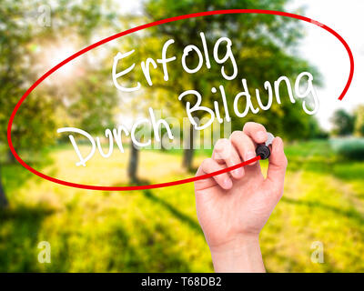 Mann Hand schreiben Erfolg durch Bildung (Erfolg durch die Ausbildung in Deutsch) mit schwarzem Marker auf visuelle Bildschirm. Stockfoto