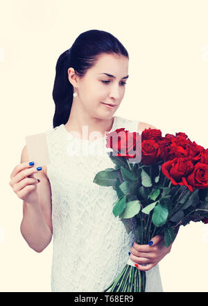 Mädchen mit Blumenstrauß aus roten Rosen und Karte in der Hand. Stockfoto
