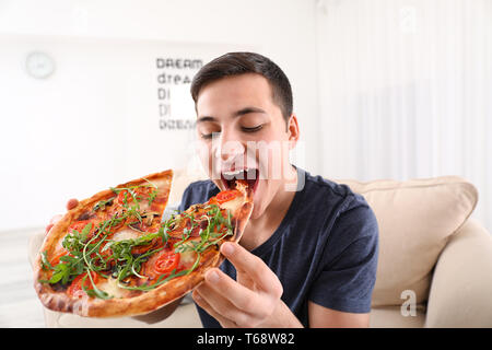 Junger Mann essen lecker Pizza zu Hause Stockfoto