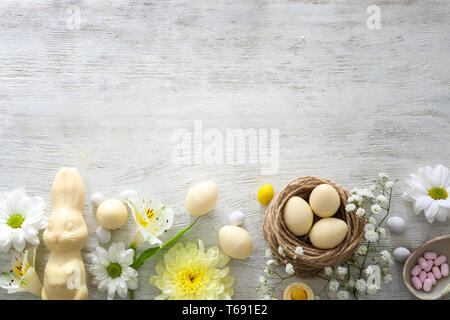 Schöne Ostern Komposition mit Schokolade Hase, Eier und Blumen auf Holz- Hintergrund, Ansicht von oben Stockfoto