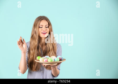 Schöne junge Frau mit bemalten Ostereier auf farbigen Hintergrund Stockfoto