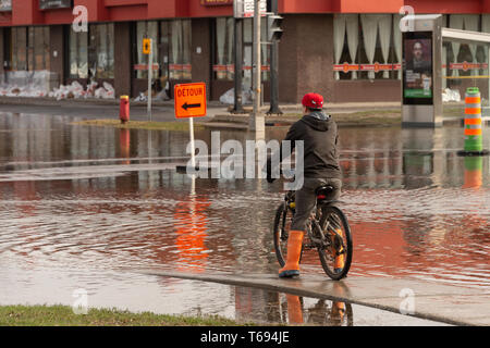 Pierrefonds-Roxboro, Quebec, Kanada - 29 April 2019: Menschen in einem versunkenen Straße im Frühjahr Hochwasser Stockfoto