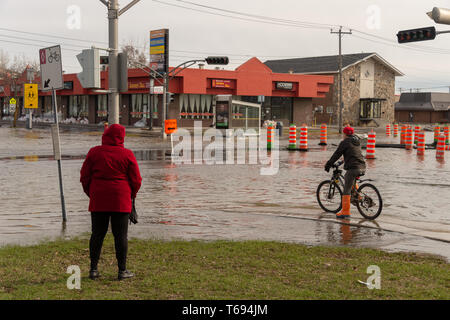 Pierrefonds-Roxboro, Quebec, Kanada - 29 April 2019: Menschen in einem versunkenen Straße im Frühjahr Hochwasser Stockfoto