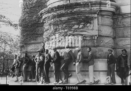 Schwarz-weiß Foto, von einer Reihe von Männern und Jungen, Balancieren auf einem Felsvorsprung des Giessens rund um die Basis der MacDonough Halle an der US Naval Academy in Annapolis, Maryland, USA; von John vachon fotografiert, unter der Schirmherrschaft von Farm Security Administration der Vereinigten Staaten, 1940. Von der New York Public Library. () Stockfoto