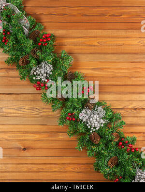 Kranz mit Weihnachtsschmuck und Tannenzapfen auf Holz- Hintergrund. Stockfoto