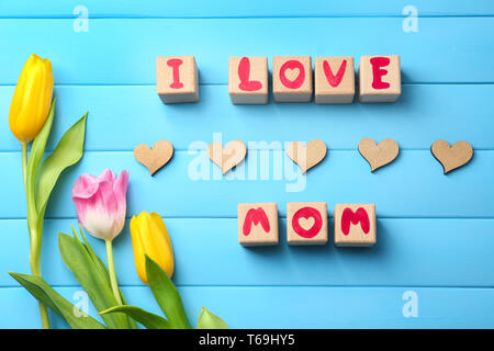 Holzblöcke mit Buchstaben, die Phrase, die ich liebe Mama und wunderschöne Blumen auf farbigen Hintergrund Stockfoto
