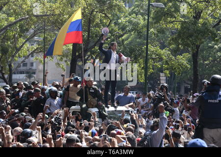 30 April 2019, Venezuela, Caracas: Juan Guaido (M.), selbst ernannten einstweiligen Präsidenten Venezuelas, steht mit zwei megaphonen in seinen Händen, umgeben von Soldaten und Zivilisten auf der Plaza Altamira. "Als interimistischer Präsident Venezuelas, als legitime Oberbefehlshaber der Armee, die ich auf alle Soldaten rufen Sie uns an", sagt der Führer der Opposition auf einer Autobahn. "Alle Venezolaner wollen Freiheit kommen sollte", sagte Oppositionsführer Lopez, die aus dem Hausarrest entlassen wurde. "In diesem Moment, alle Venezolaner, uniformierten und einheitliche benannte, sind auf die Straße gegangen zu sein." Foto: Rafael Hernan Stockfoto