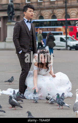 Glasgow, Schottland, Großbritannien. 30. April, 2019. UK Wetter. Eine braut Feeds die Tauben neben der Bräutigam während Hochzeitsfotos auf einen Nachmittag des regnerischen Intervalle auf dem George Square. Credit: Skully/Alamy leben Nachrichten Stockfoto