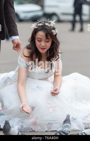 Glasgow, Schottland, Großbritannien. 30. April, 2019. UK Wetter. Eine braut Feeds die Tauben neben der Bräutigam während Hochzeitsfotos auf einen Nachmittag des regnerischen Intervalle auf dem George Square. Credit: Skully/Alamy leben Nachrichten Stockfoto