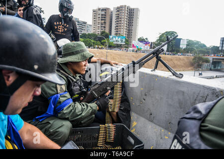 Caracas, Miranda, Venezuela. 30 Apr, 2019. Ein anti Regierung Soldat mit Maschinengewehr die Stelle für den Kampf bereit. venezolanischen Militärs, die Unterstützung der venezolanischen Opposition leader Juan Guaido sind auf die Strasse mit ihren Waffen zusammen mit der Regierung die Demonstranten in einem Militärputsch gegen die sozialistische Regierung unter der Führung von Präsident Nicolas Maduro. Credit: Roman Camacho/SOPA Images/ZUMA Draht/Alamy leben Nachrichten Stockfoto