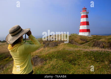 Eine junge Frau an einem Leuchtturm mit dem Fernglas suchen Stockfoto