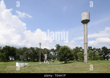 Silber Wasserturm unter grünen Gras und Bäume Stockfoto