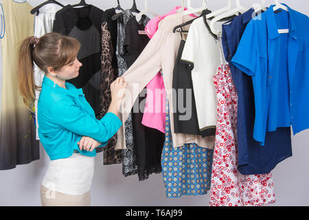 Junges Mädchen wählt sorgfältig Kleidung im Kleiderschrank Stockfoto