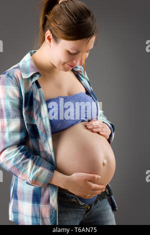 Schwangere Frau streichelt ihren Bauch Stockfoto