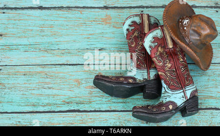 Braun und Blau Cowboystiefel und braunen Hut auf einem rustikalen blau Holz Hintergrund mit Writing Space Stockfoto