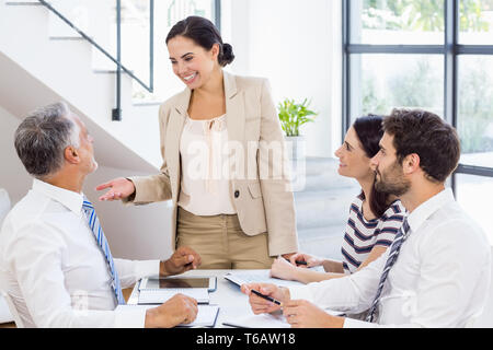 Eine Geschäftsfrau ist im Gespräch mit ihren Kollegen, die ihr hören Stockfoto