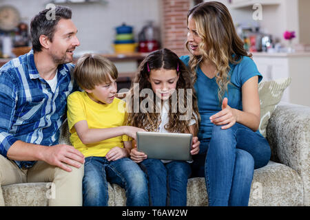 Eltern und Kinder auf Sofa sitzen und mit einem digital-Tablette Stockfoto