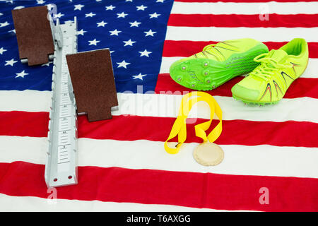 Trainer Schuhe, Startblock und Goldmedaille auf amerikanische Flagge Stockfoto