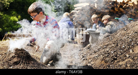 Jungen mit Rauchen Holzkohle Pile, Ennepetal, Ruhrgebiet, Nordrhein-Westfalen, Deutschland Stockfoto