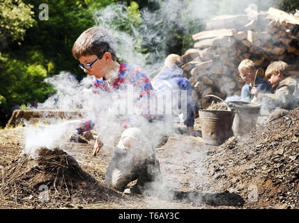 Jungen mit Rauchen Holzkohle Pile, Ennepetal, Ruhrgebiet, Nordrhein-Westfalen, Deutschland Stockfoto