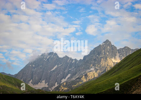 Niedrige Wolken, Stratus Wolken direkt über dem hoch aufragenden Berge des Himalaja in Kaschmir mit tief blauen Himmel. Sonnenaufgang auf dem mountainsin Himalaya. Stockfoto