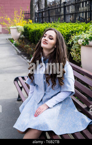 Schöne lächelnde junge Dame im blauen Anzug mit langen Haaren auf der Straße der Europäischen Stadt posing Stockfoto