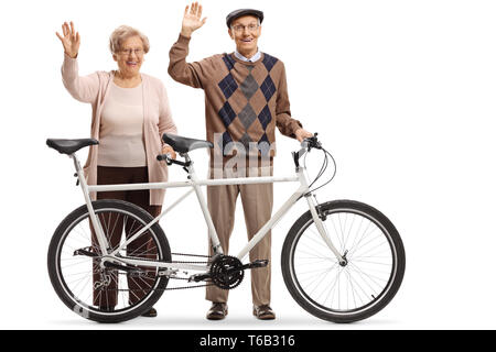 In voller Länge Porträt eines älteren Paares von Mann und Frau mit einem Tandem Fahrrad winken auf weißem Hintergrund Stockfoto