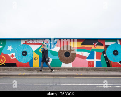 Eine Person geht von einem wandbild an der Eisenbahnbrücke in Mill Road Cambridge UK lackiert Stockfoto