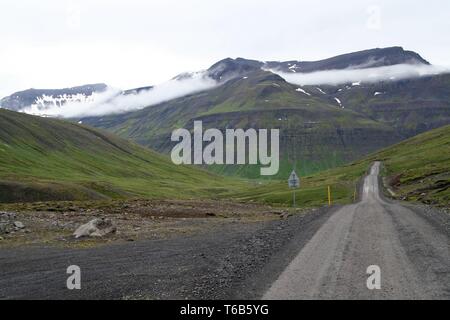 Einsamen endlosen Schmutz Straße zum Berg Gesicht mit tief hängenden Wolken - Island Stockfoto