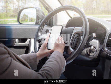 Junge weibliche Fahrer mittels Touchscreen Smartphone und GPS-Navigation im Auto Stockfoto