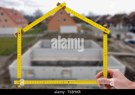 Shell von Haus im Bau mit Zollstock in der Hand von Real estate agent Stockfoto