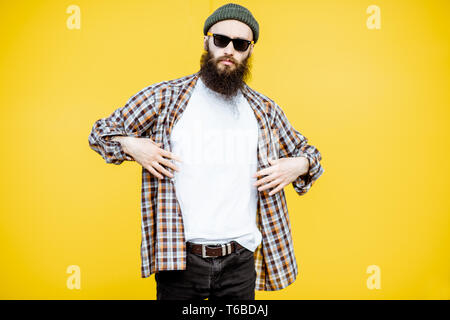 Porträt einer coolen Mann im Hemd und Hut posiert auf der hellen gelben Hintergrund Stockfoto