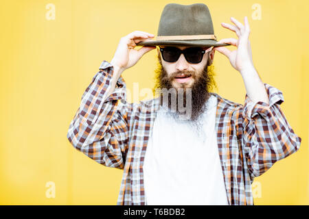 Porträt einer coolen Mann im Hemd und Hut posiert auf der hellen gelben Hintergrund Stockfoto