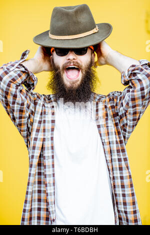 Porträt einer coolen Mann im Hemd und Hut posiert auf der hellen gelben Hintergrund Stockfoto