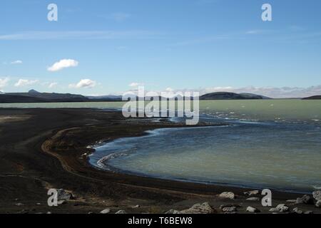 Hálslón See mit schwarzen vulkanischen Strand und die schneebedeckten Berge in Island Stockfoto