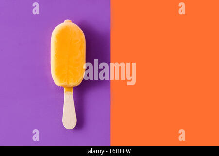Orange popsicle auf Violett und Orange hinterlegt. Copyspace Stockfoto