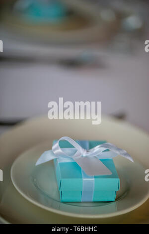 Festliche Tischdekoration mit handgefertigten Geschenkbox an der Platte. Hellblau handgefertigten Geschenkbox in der Platte auf Hochzeit Tisch. Stockfoto