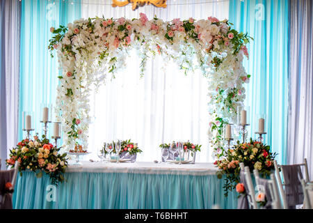 Festlich mit Blumen geschmückt. Hochzeitstisch mit Blumensträußen, Kerzen, Gläser und Geschirr. Dekorationen und Einstellung für Hochzeit Stockfoto