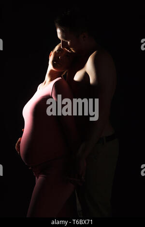 Schwangere junge Frau mit Mann im Studio Stockfoto