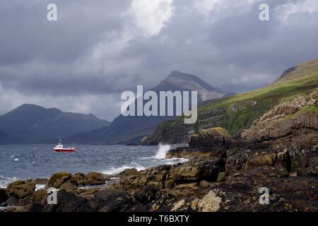 Kleine rote Fischerboot auf dem Loch Scavaig, dominiert von der Cullin Mountains auf einem Stimmungsvollen Herbsttag. Elgol, Isle of Skye, Schottland, Großbritannien. Stockfoto