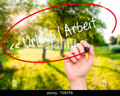 Mann Hand schreiben Uralaub Arbeit (Urlaub - Arbeiten in Deutscher Sprache) mit schwarzem Marker auf visuelle Bildschirm. Stockfoto