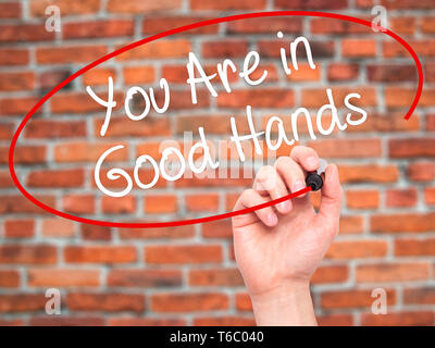 Mann Hand schreiben sind Sie in guten Händen mit schwarzem Marker auf visuelle Bildschirm Stockfoto